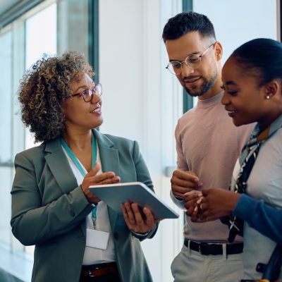 Happy multiracial couple and their financial advisor using touchpad on a meeting in the office.